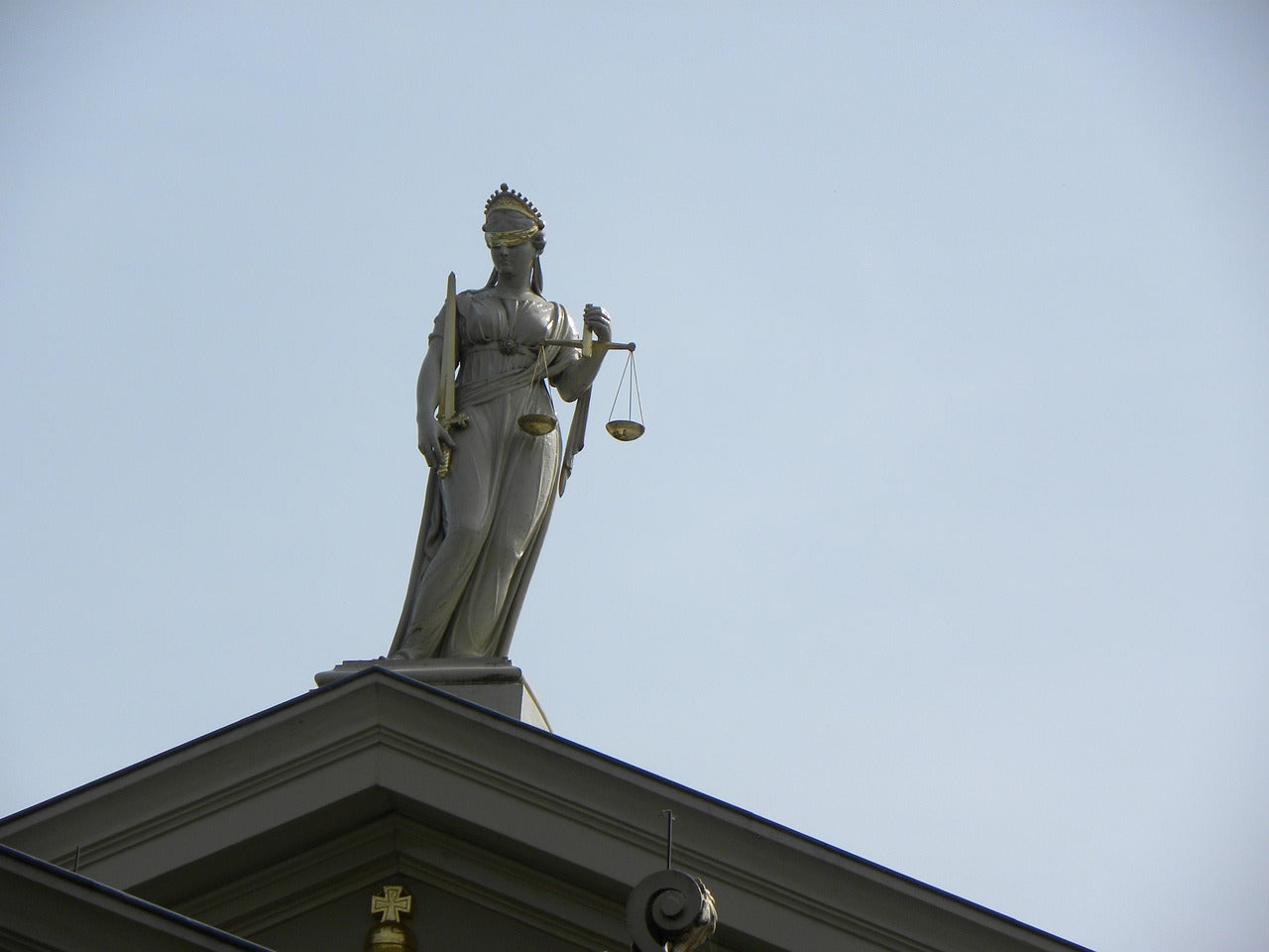 Justitia statue holding scales above a courthouse roof