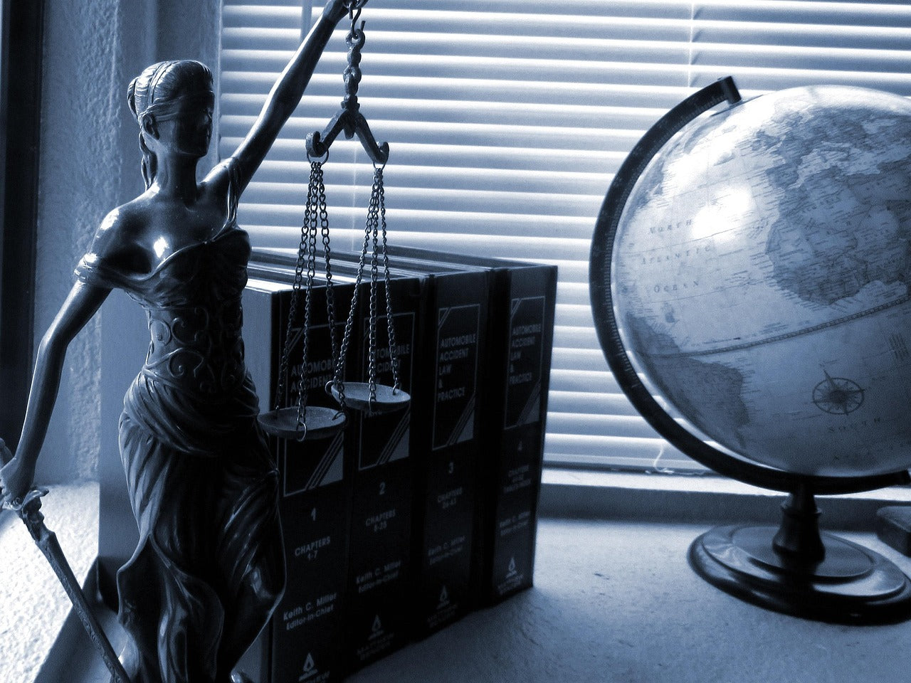 Lady Justice statuette beside law books in a dark office